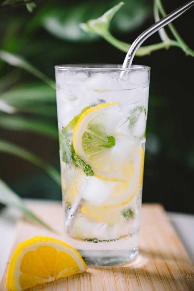 Lemon water in a glass of ice with a straw.